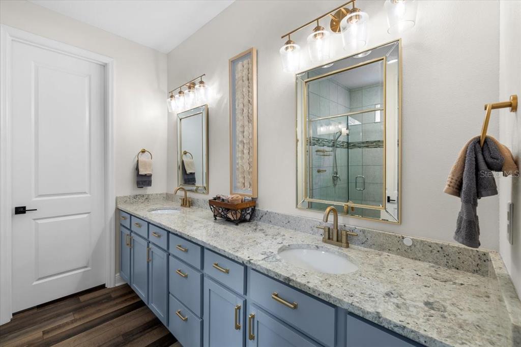 A bathroom features a double vanity with blue cabinets, granite countertops, and gold-toned fixtures — 7 BELLIS COURT, HOMOSASSA, FL