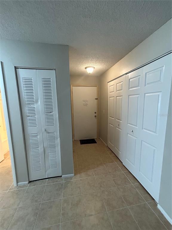 An entryway features tiled flooring, a white front door, and two sets of closet doors — 636 KENWICK CIRCLE UNIT 105, CASSELBERRY, FL