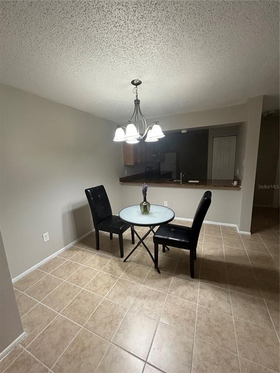 A dining area features a small round table, two black chairs, and a chandelier — 636 KENWICK CIRCLE UNIT 105, CASSELBERRY, FL