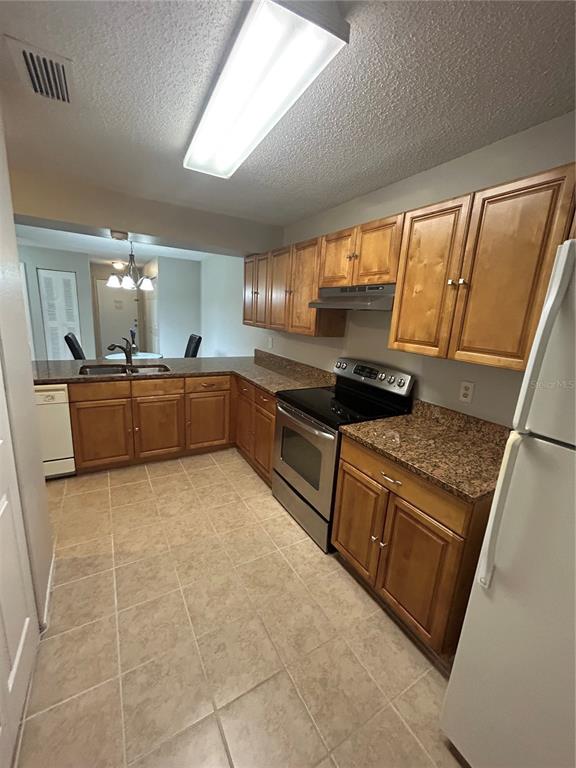 A kitchen features wood cabinets, granite countertops, stainless steel appliances, and tile flooring — 636 KENWICK CIRCLE UNIT 105, CASSELBERRY, FL