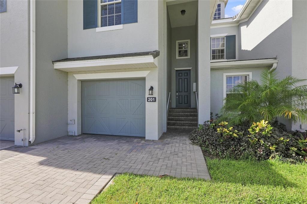 A two-story townhouse exterior features a gray garage door, a front entrance, and paved driveway — 16560 GOLDENROD LANE UNIT 201, ALVA, FL