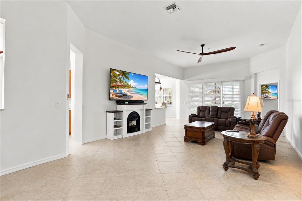 A living room features tile flooring, a white fireplace console, and brown leather furniture — 16560 GOLDENROD LANE UNIT 201, ALVA, FL