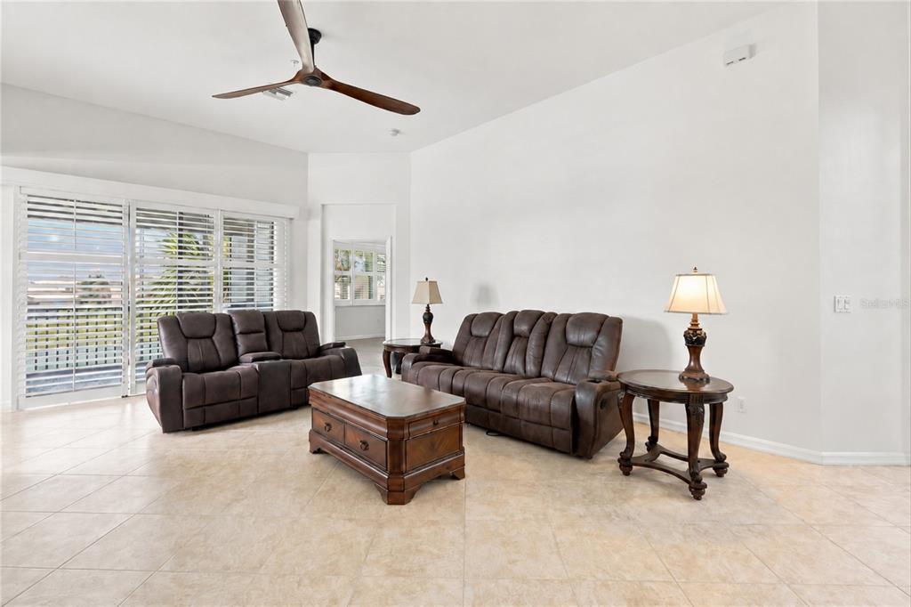 A living room features brown reclining sofas, a wooden coffee table, and tile flooring — 16560 GOLDENROD LANE UNIT 201, ALVA, FL
