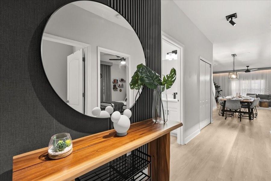 A wooden console table with decor sits beneath a round mirror on a slatted wall — 8990 CUBAN PALM ROAD, KISSIMMEE, FL
