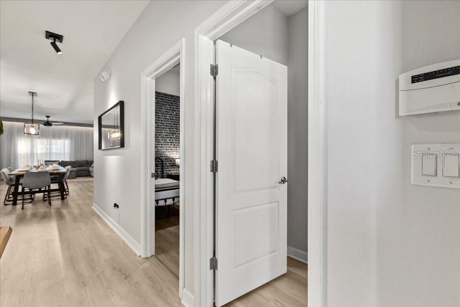 A hallway with light wood flooring leads to a dining area and a bedroom — 8990 CUBAN PALM ROAD, KISSIMMEE, FL
