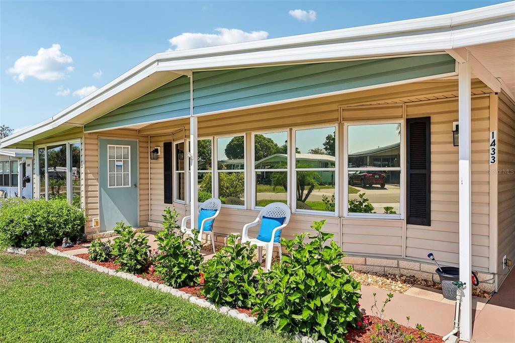 A single-story mobile home with tan siding, a light blue door, and a front porch — 1433 APACHE CIRCLE, TAVARES, FL