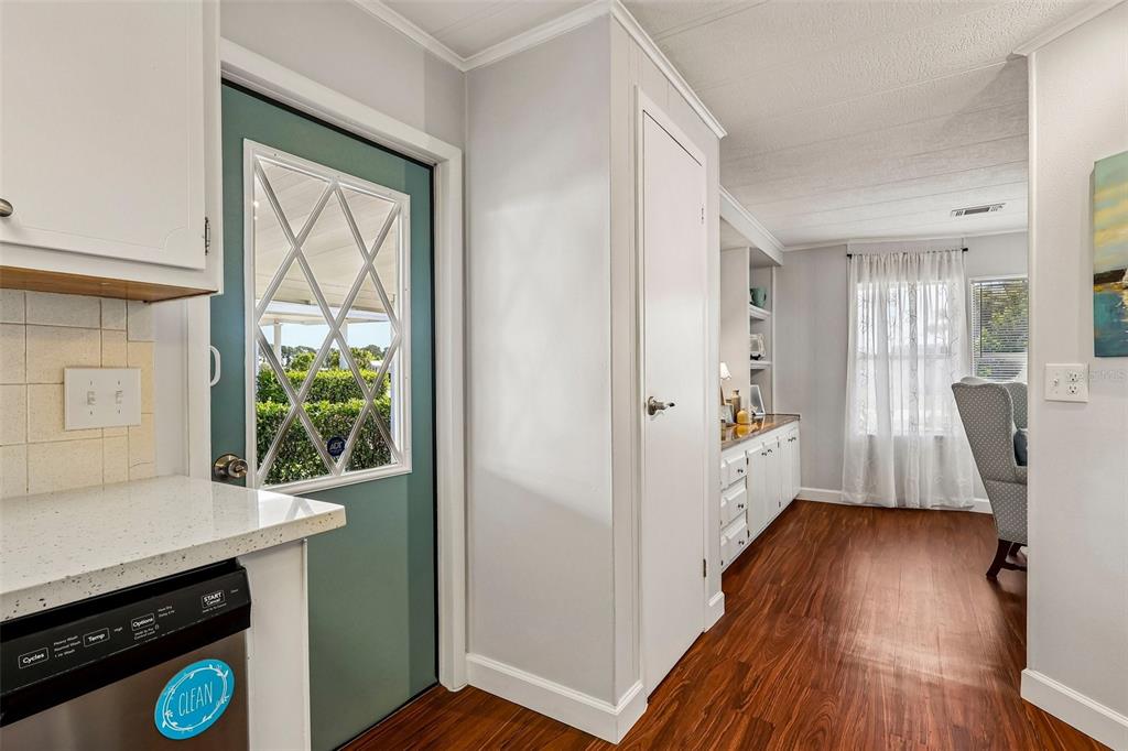 A kitchen area features a teal door, white cabinets, and wood-look flooring — 1433 APACHE CIRCLE, TAVARES, FL
