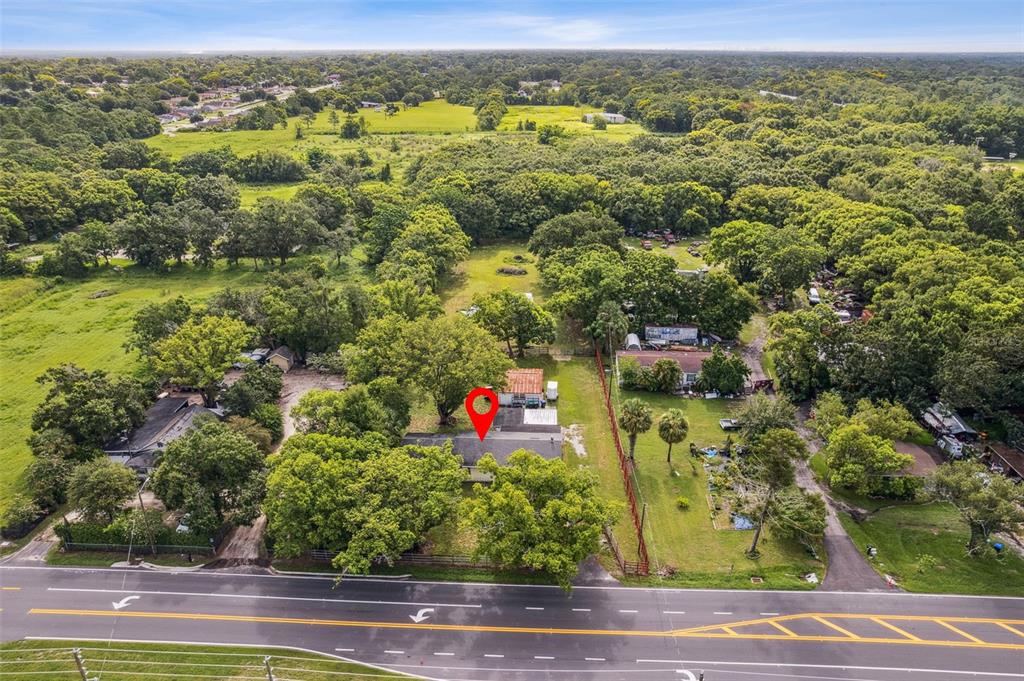 An aerial view shows a house with a red pin located on a wooded lot — 1001 OCOEE APOPKA ROAD, OCOEE, FL