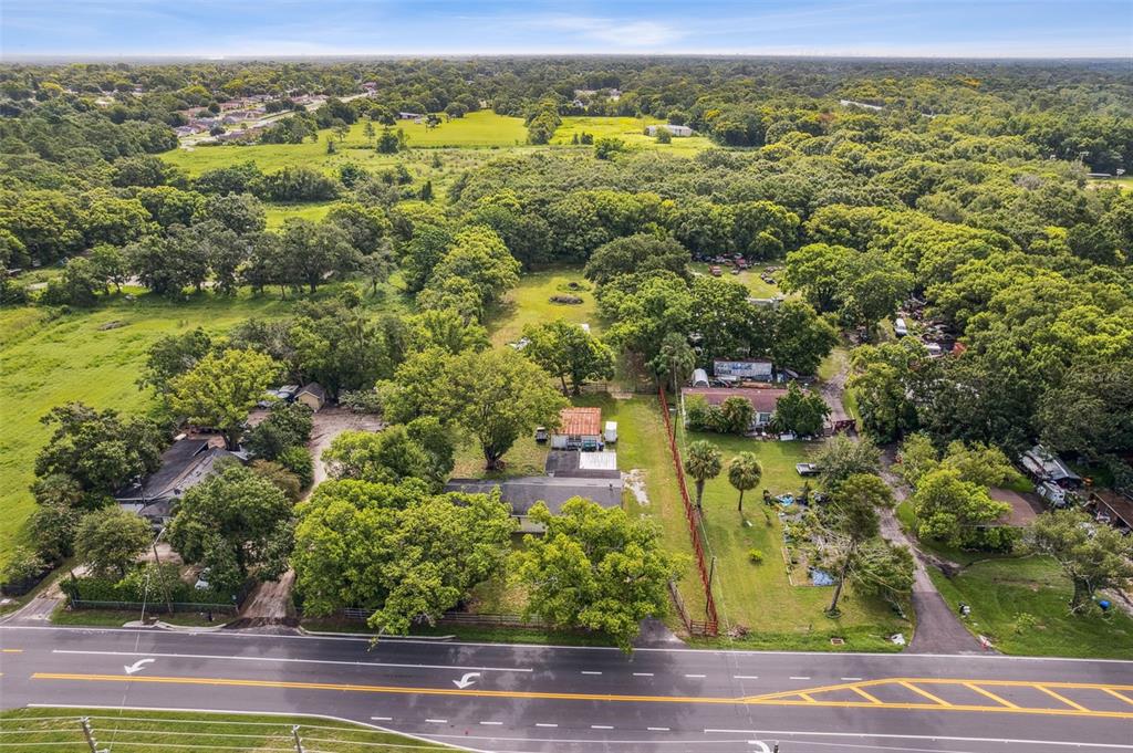 An aerial view shows two adjacent properties with houses, trees, and driveways along a road — 1001 OCOEE APOPKA ROAD, OCOEE, FL
