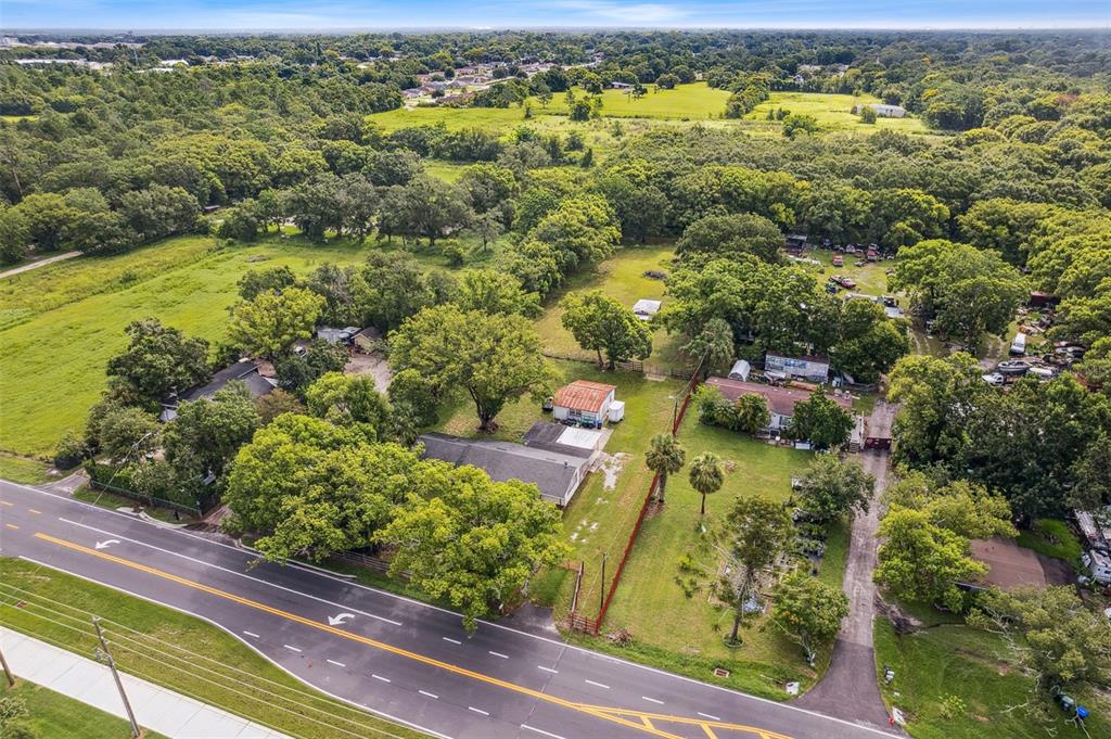An aerial view shows a rural property with multiple buildings, trees, and a paved road — 1001 OCOEE APOPKA ROAD, OCOEE, FL