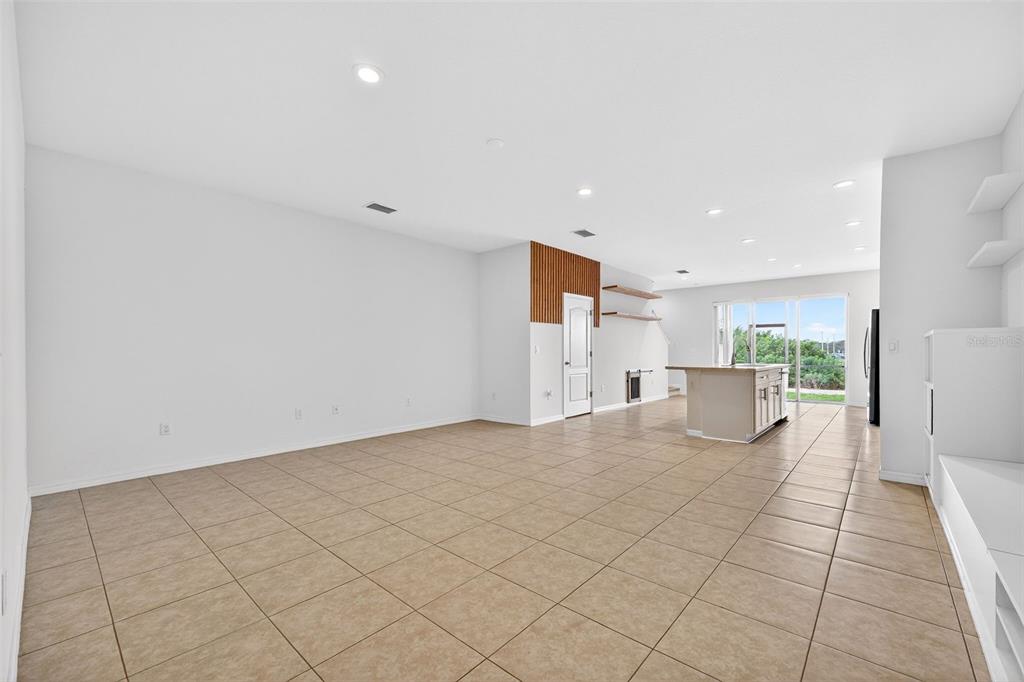 An open-concept living area features light tile flooring, white walls, and a kitchen island — 8667 CANYON CREEK TRAIL, PARRISH, FL