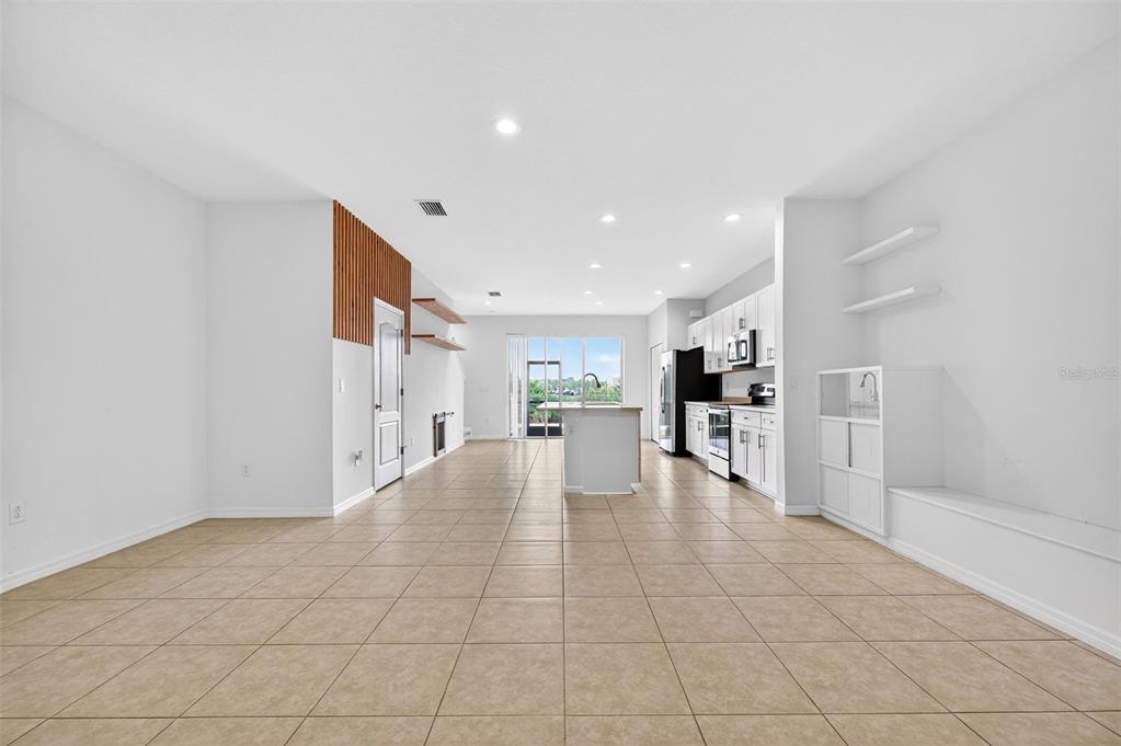 An open-concept living and kitchen area features light tile flooring and white cabinetry — 8667 CANYON CREEK TRAIL, PARRISH, FL