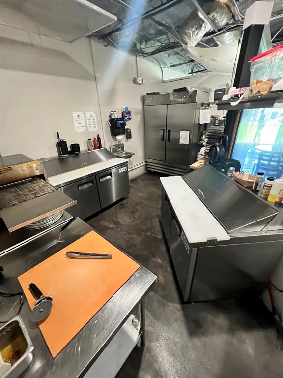 A commercial kitchen features stainless steel prep tables, refrigeration units, and a pizza cutter — 235 NE WATULA AVENUE, OCALA, FL