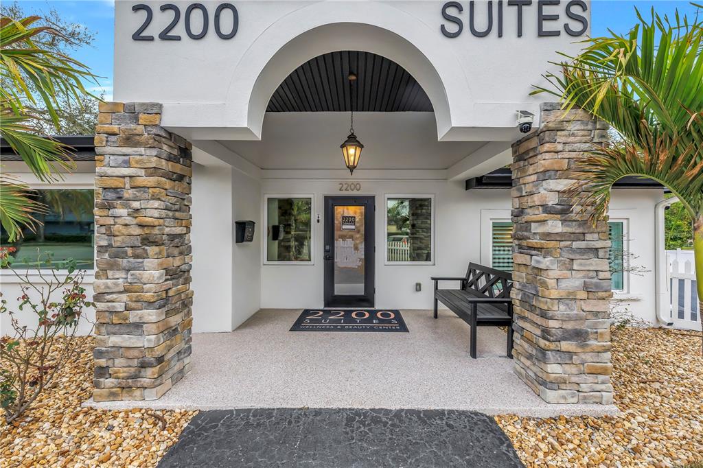 The exterior entrance of a building features stone pillars, a white archway, and a bench — 2200 49TH STREET N, ST PETERSBURG, FL
