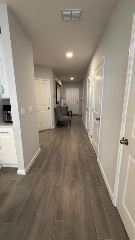 An entryway features gray wood-look tile flooring, a carpeted staircase, and a light blue door — 5007 PRAIRIE PRESERVE RUN, ST CLOUD, FL