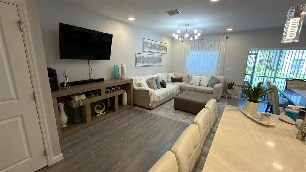 A living room features a sectional sofa, a television on a console, and tile flooring — 5007 PRAIRIE PRESERVE RUN, ST CLOUD, FL