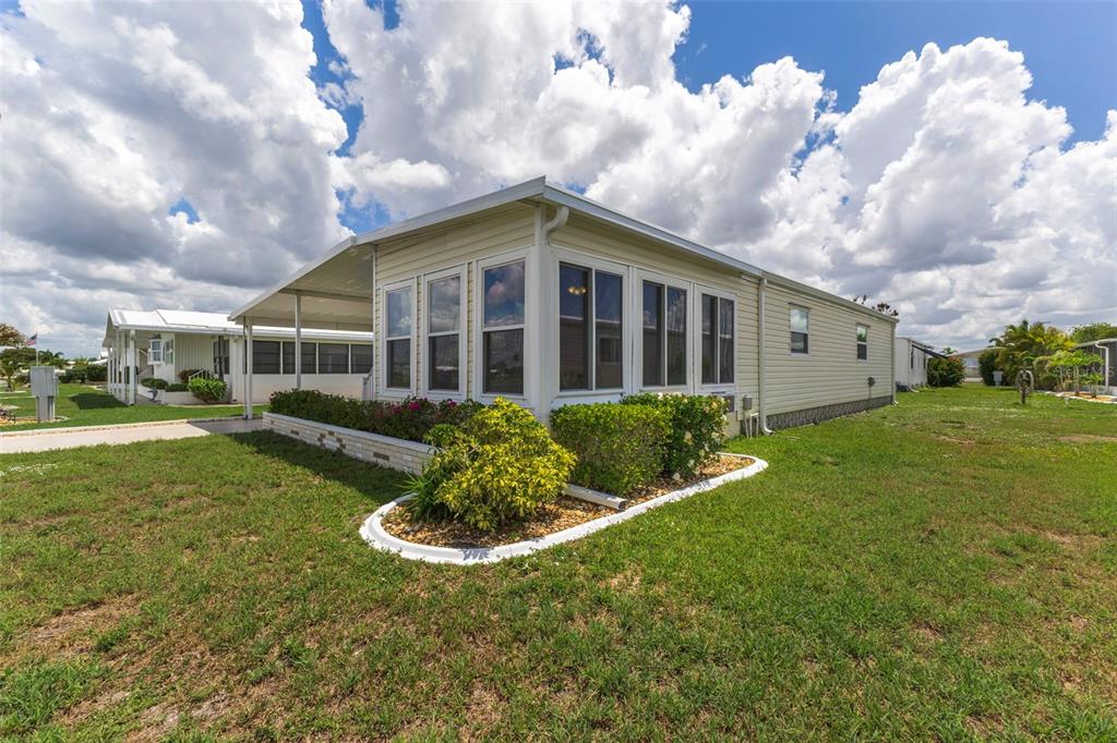 A light-colored manufactured home features a screened-in porch and a landscaped garden bed — 716 SANCHEZ CIRCLE, NORTH PORT, FL