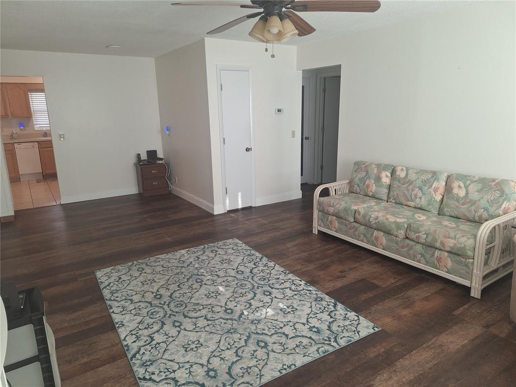 A living room with wood-look flooring, a floral sofa, and a patterned area rug — 8447 AUSTIN N UNIT 8447, PINELLAS PARK, FL