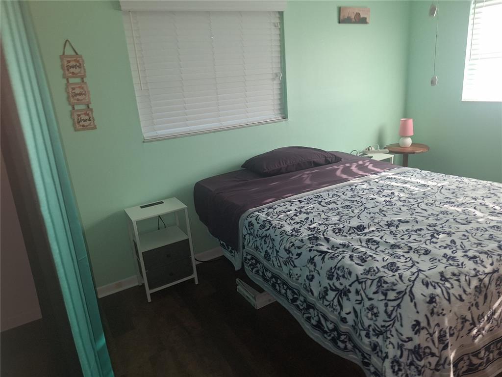 A bedroom with mint green walls, a bed with a patterned quilt, and two nightstands — 8447 AUSTIN N UNIT 8447, PINELLAS PARK, FL