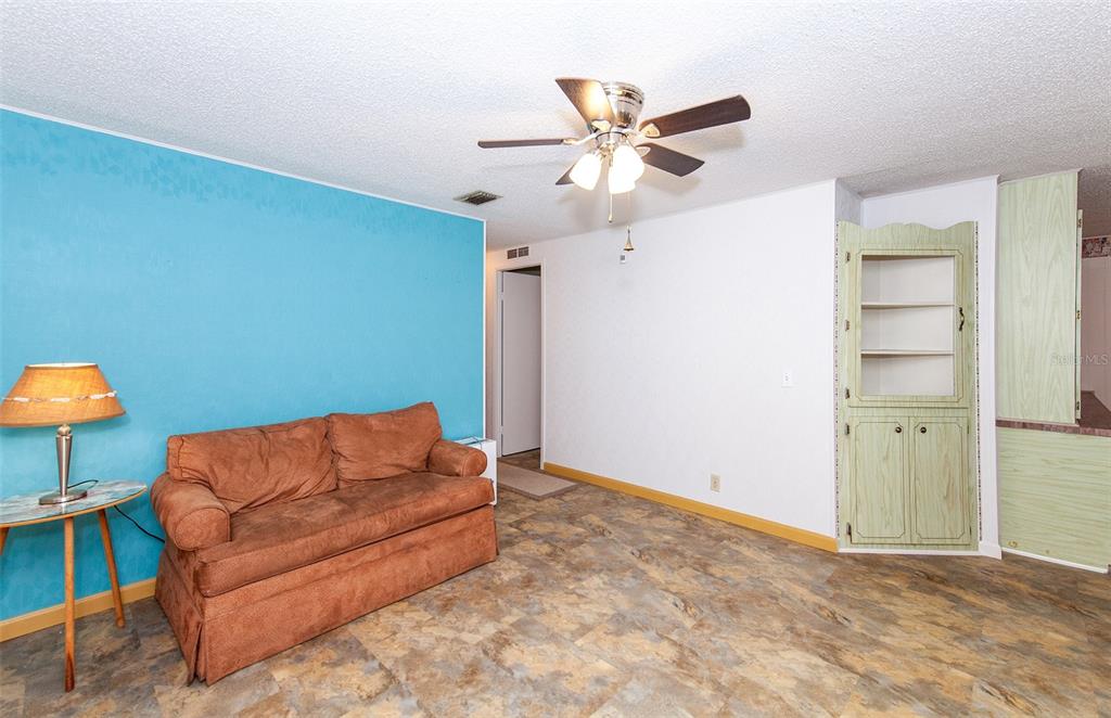 A living room features a blue accent wall, a brown sofa, and a built-in cabinet — 878 JOLANDA CIRCLE, VENICE, FL