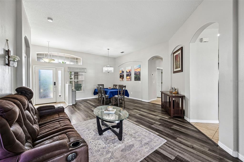 A living and dining area features wood-look flooring, a brown recliner, and a glass table — 2910 127TH PLACE E, PARRISH, FL