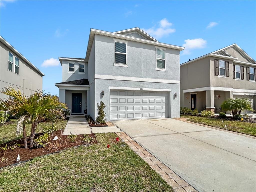 A two-story light gray house with a two-car garage and a paved driveway — 6312 MILESTONE LOOP, PALMETTO, FL