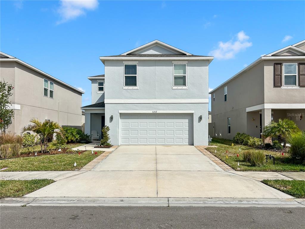 A two-story light blue house with a two-car garage and a concrete driveway — 6312 MILESTONE LOOP, PALMETTO, FL