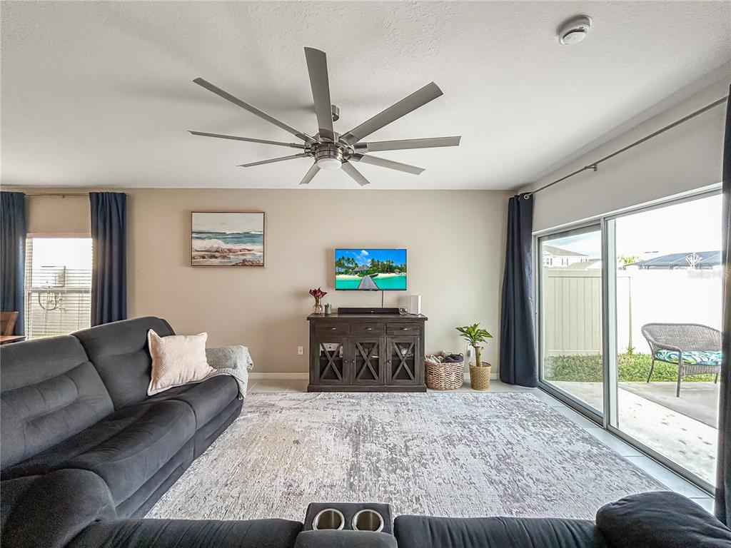 A living room features a large gray sectional sofa, a ceiling fan, and a sliding door — 6312 MILESTONE LOOP, PALMETTO, FL
