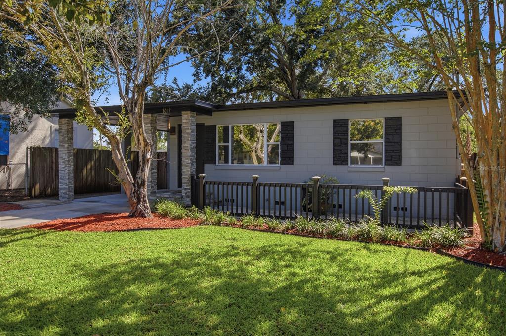 A single-story house with a gray block exterior, black shutters, and a front porch fence — 1017 N GLENWOOD AVENUE, ORLANDO, FL
