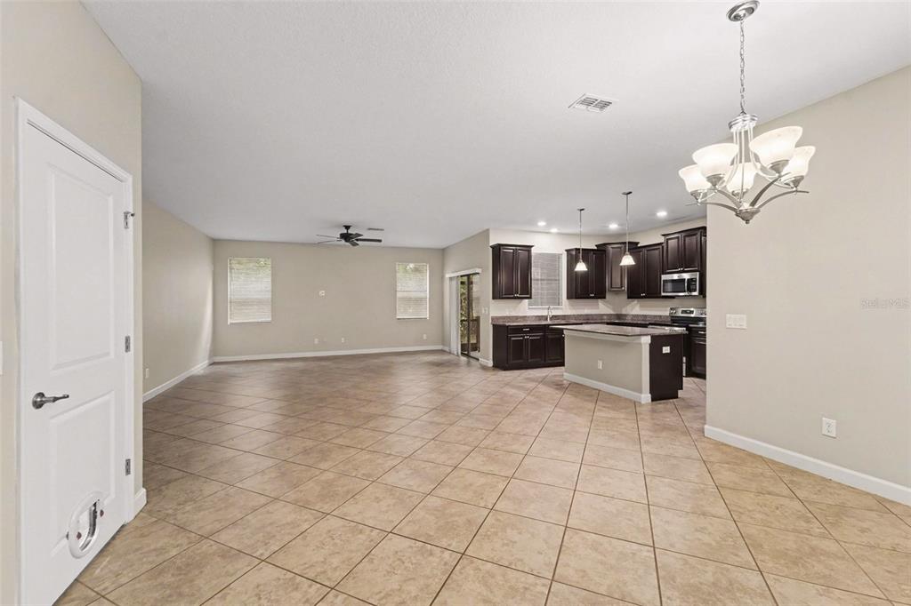 An open-concept living area features tile flooring, dark wood kitchen cabinets, and a central island — 17335 OLD TOBACCO ROAD, LUTZ, FL