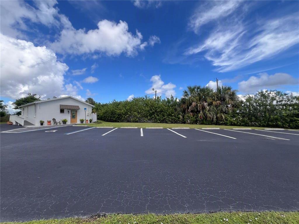 A white building with a parking lot in the foreground under a blue sky — 180 RIO VILLA DRIVE, PUNTA GORDA, FL