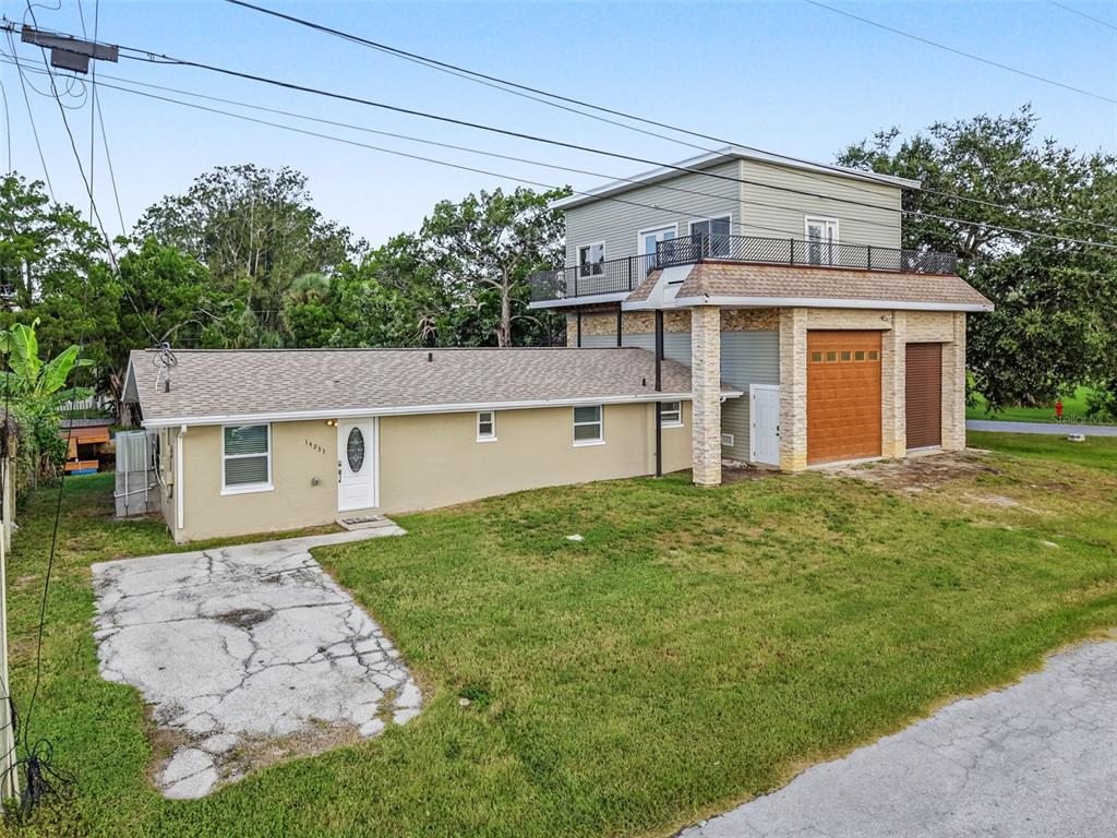 An exterior view of a single-story home attached to a two-story garage with a balcony — 14233 SHILOH COURT, HUDSON, FL