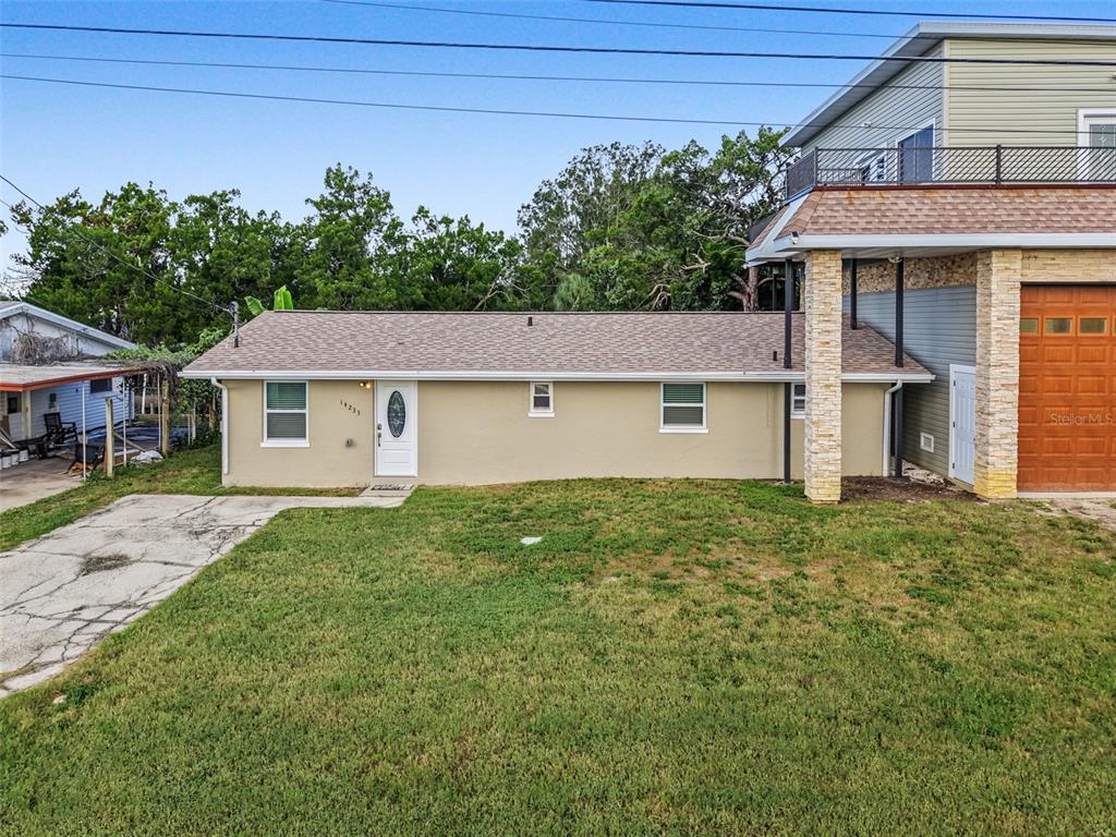 A tan, single-story house with a white door and an adjacent two-story structure — 14233 SHILOH COURT, HUDSON, FL