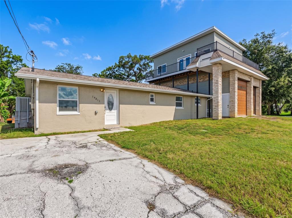 A single-story house is attached to a two-story structure with a garage and balcony — 14233 SHILOH COURT, HUDSON, FL