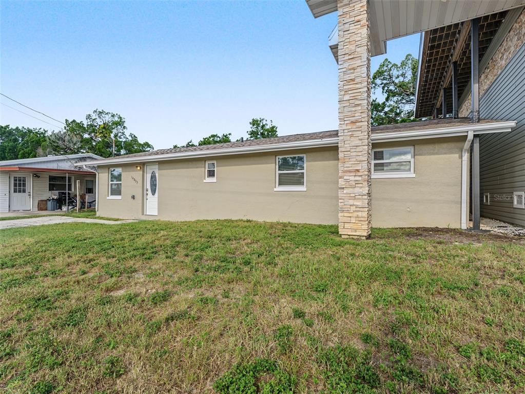 A tan single-story house exterior features a stone column and a white front door — 14233 SHILOH COURT, HUDSON, FL
