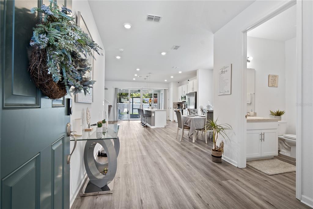 A view from an entryway into an open-concept living area with wood-look flooring — 1125 MATTIE POINTE BOULEVARD, AUBURNDALE, FL
