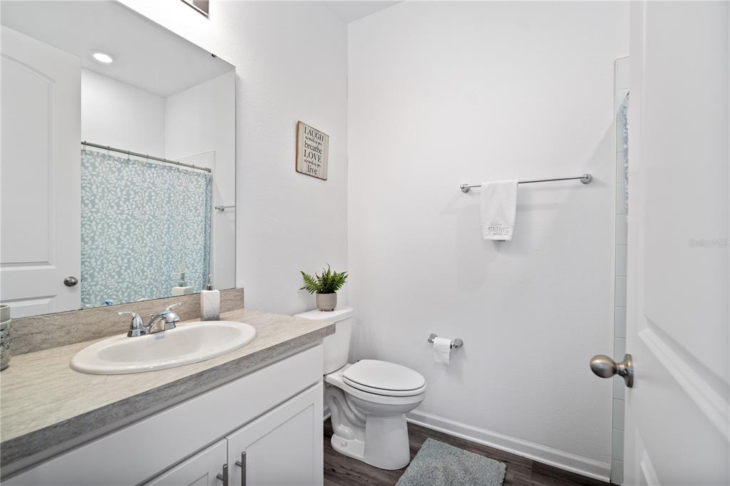 A bathroom features a white vanity with a sink, a toilet, and a shower curtain — 1125 MATTIE POINTE BOULEVARD, AUBURNDALE, FL