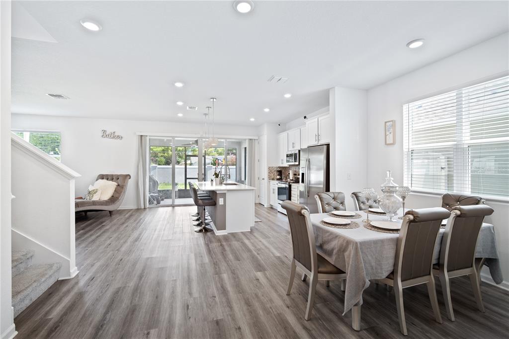 An open-concept kitchen and dining area with light wood-look flooring and white cabinetry — 1125 MATTIE POINTE BOULEVARD, AUBURNDALE, FL