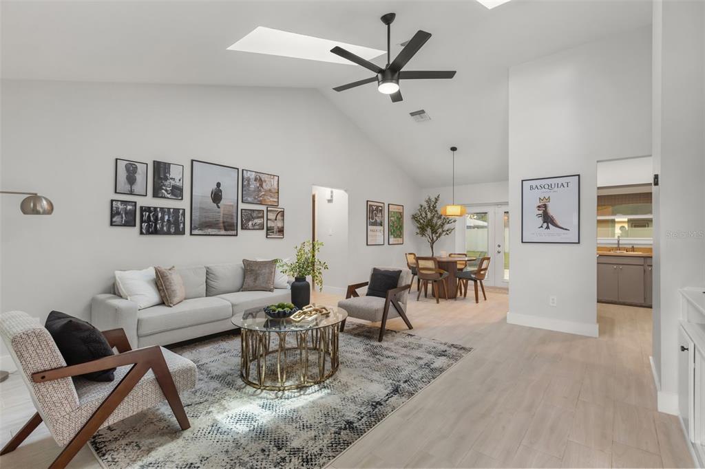 A living room with a vaulted ceiling, a ceiling fan, and a dining area beyond — 7384 GRAND AVENUE, WINTER PARK, FL