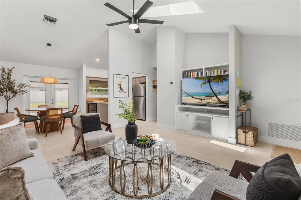 A bright living room features a glass coffee table, two armchairs, and a built-in media center — 7384 GRAND AVENUE, WINTER PARK, FL