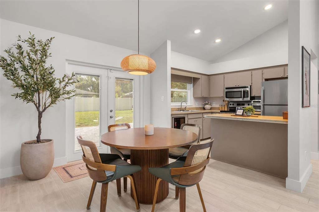 A dining area with a round table and pendant light sits adjacent to a kitchen — 7384 GRAND AVENUE, WINTER PARK, FL