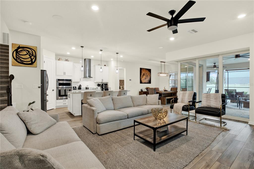 A living room features light-colored sofas, a wood media console, and a sliding glass door — 19234 MOSSY PINE DRIVE, TAMPA, FL