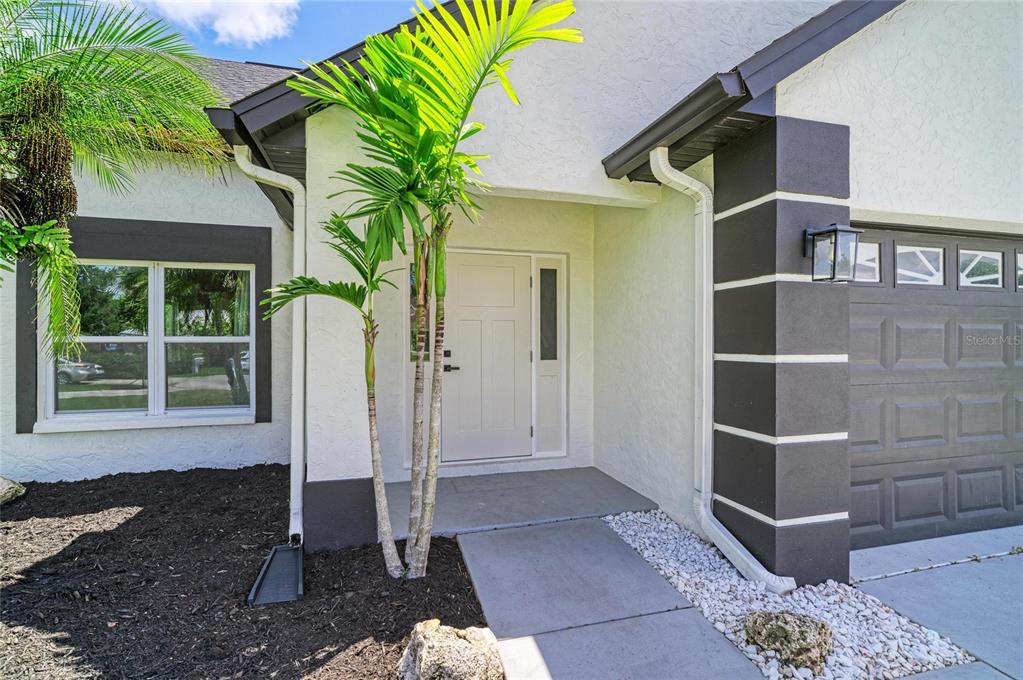 The exterior of a house features a white front door, a palm tree, and garage — 3220 37TH TERRACE E, BRADENTON, FL