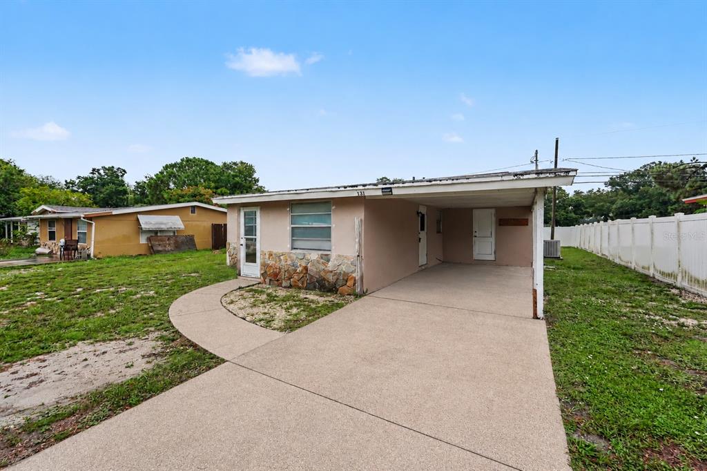 A single-story house with a carport, stone facade accents, and a concrete driveway — 131 EMERALD LANE, LARGO, FL
