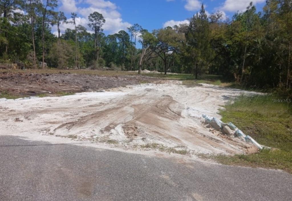 A cleared, sandy residential lot sits adjacent to a paved road under a blue sky — 1013 CUPID AVENUE, CHRISTMAS, FL