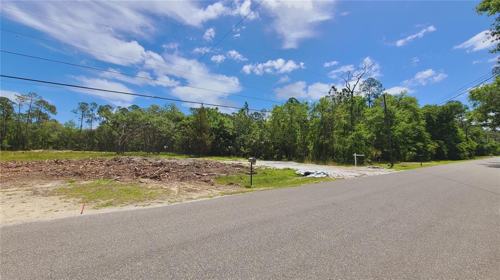A cleared, vacant lot sits beside a paved road under a blue sky — 1013 CUPID AVENUE, CHRISTMAS, FL