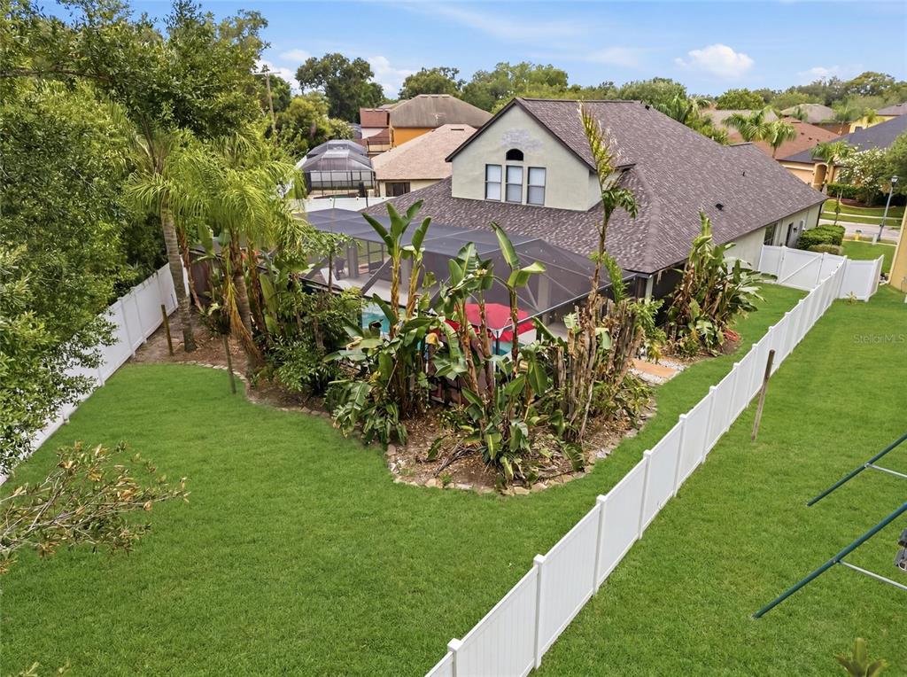 An aerial view of a backyard featuring a screened-in pool, landscaping, and a white fence — 1945 ABBEY RIDGE DRIVE, DOVER, FL