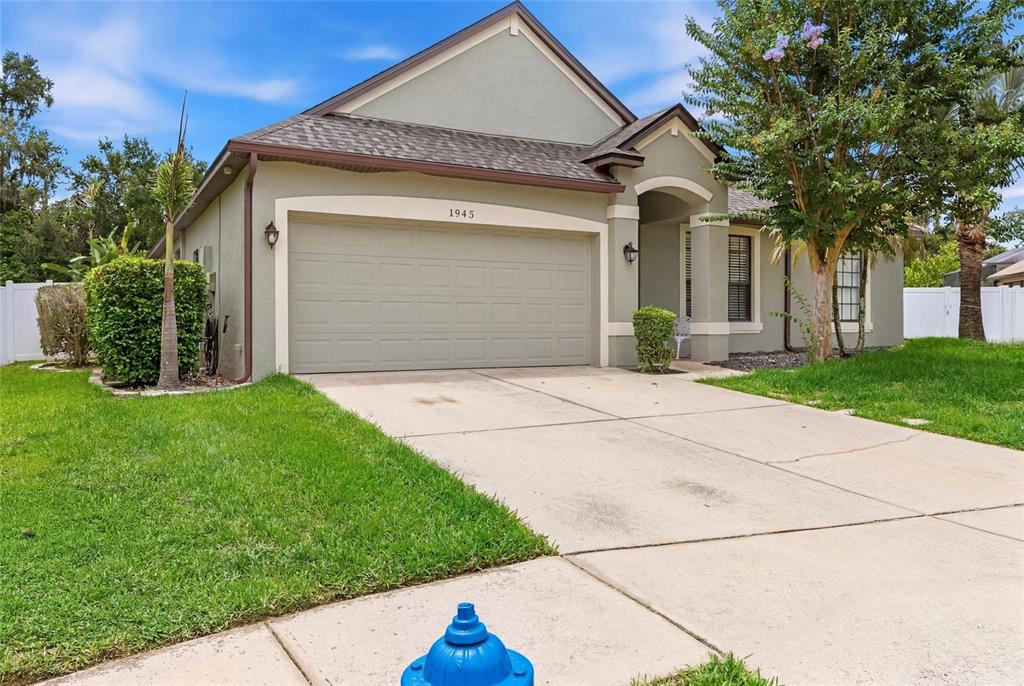 A single-story house with a beige stucco exterior, a two-car garage, and a blue fire hydrant — 1945 ABBEY RIDGE DRIVE, DOVER, FL