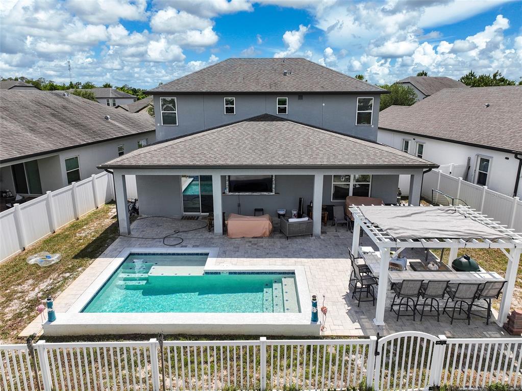 A two-story house features a covered patio, a rectangular swimming pool, and a pergola — 3415 FEATHERGRASS CT, ST CLOUD, FL