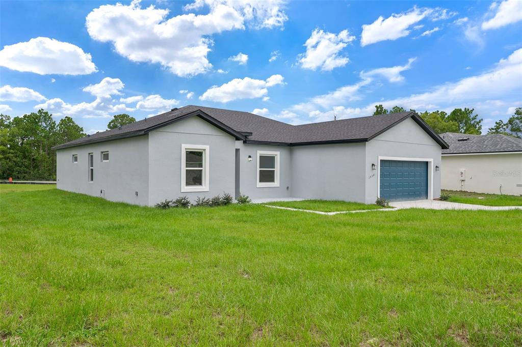 A single-story gray house with a blue garage door sits on a grassy lot — 15301 SW 50TH AVENUE ROAD, OCALA, FL